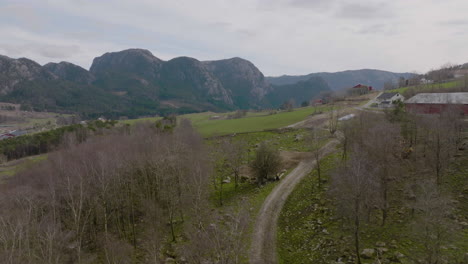 Aerial-drone-flyover-of-the-mountainous-farm,-following-gravel-road