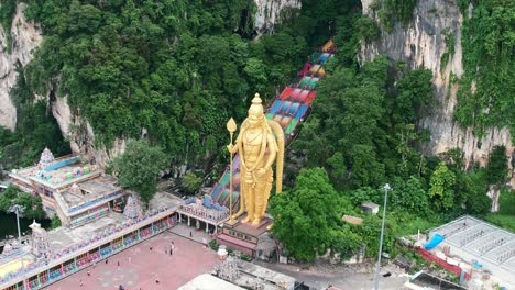 Luftdrohne-Umkreist-Die-Lord-Murugan-Statue-Mit-Einer-Bunten-Treppe,-Die-Zu-Den-Batu-Höhlen-In-Kuala-Lumpur,-Malaysia-Führt,-An-Einem-Bewölkten-Nachmittag-Ohne-Touristen