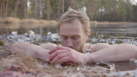 ZOOM-IN---An-ice-bather-focuses-on-conscious-breathing-as-he-sits-in-a-frozen-lake
