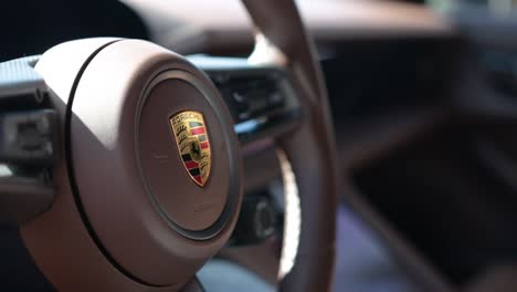Close-up-Porsche-badge-on-steering-wheel-of-Taycan-sports-car