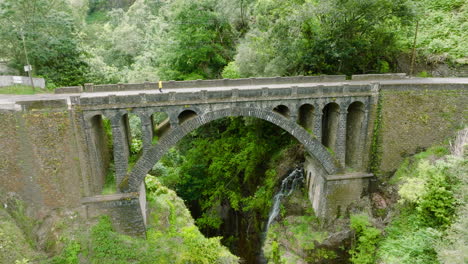 Person-crossing-ancient-arch-bridge,-A-Ponte-Velha,-Madeira