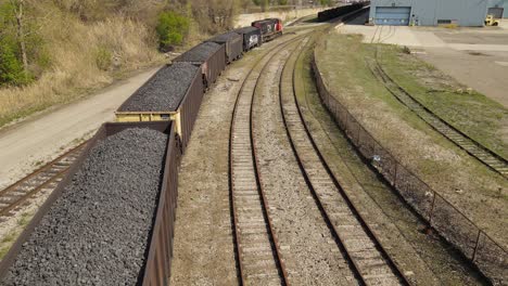 Heavy-industrial-railroad-carts-filled-with-coal-hauled-by-train,-aerial-view