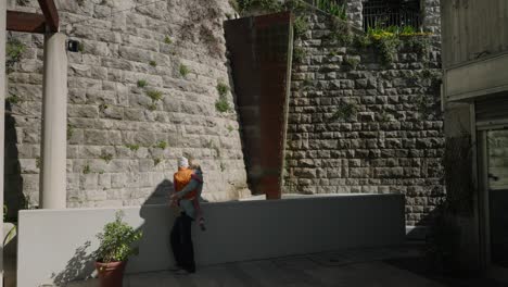 Eine-Mutter-Mit-Ihrem-Kind-Blickt-Auf-Einen-Brunnen-Neben-Historischen-Mauern-In-Triest,-Italien