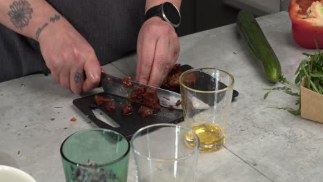 Oily-sundried-tomato-is-cut-up-on-small-kitchen-counter-cutting-board