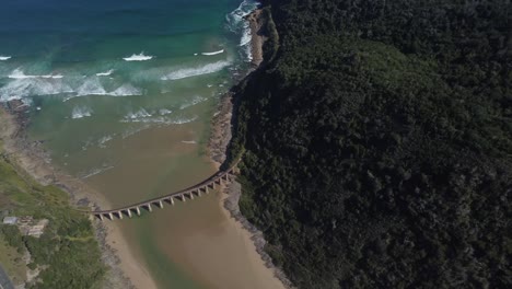 Birds-eye-drone-shot-of-Wilderness-beach-in-South-Africa---drone-is-circling-around-the-old-railway-bridge