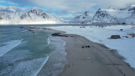 Sandy-beach-in-Norway-covered-in-snow-on-a-sunny-moody-day,-Flakstad-Beach-Lofoten,-Aerial-view,-forward-shot