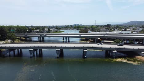 Overtake-Shot-Of-Two-Bridges-Busy-With-Cars-Crossing-Over-Beautiful-Long-Lagoon,-San-Mateo,-California