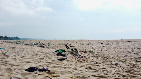 Low-aerial-flying-over-beach-sand-with-garbage,-Vietnam