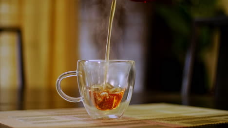 Nahaufnahme-Eines-Afroamerikanischen-Mannes,-Der-Dampfend-Heißen-Tee-In-Eine-Transparente-Teetasse-Aus-Glas-Gießt
