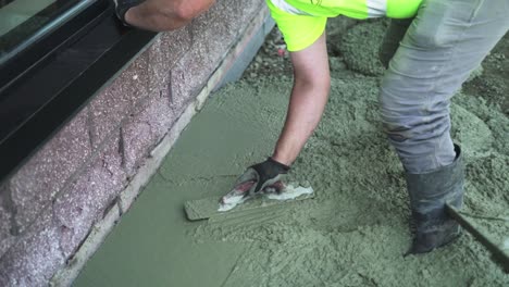 Construction-worker-spreading-concrete-cement-flooring-with-trowel