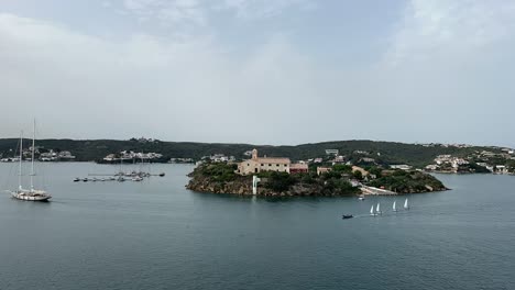 Timelapse-of-the-King’s-island,-in-Menorca,-Spain,-a-great-natural-bay,-with-many-sailboats,-in-a-race-in-a-cloudy-day