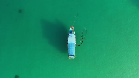 Aerial-view-of-diving-boat-with-a-group-of-divers-embarking-in-pristine-beauty-turquoise-ocean-water,-amazing-diving-adventure