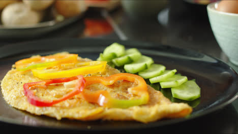 Close-up-of-man-garnishing-omelet-with-diced-peppers