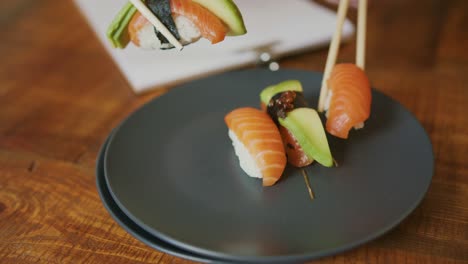 Eating-the-Japanese-way-with-Sushi,-Salmon-and-avocado-using-chopsticks-only