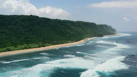 Breite-Luftaufnahme-Der-Bergküste-Von-Bali-In-Uluwatu-Mit-Wellen,-Die-Am-Strand-Von-Nyang-Nyang-Krachen