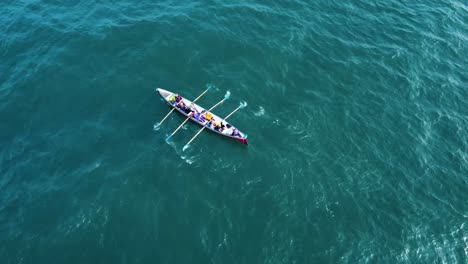 a-solo-rowing-boat,-rowing-out-at-sea,-off-the-coast-of-the-UK,-on-a-summers-day,-filmed-with-a-Dji-Mavic-drone,-which-pans-up-to-reveal-the-the-horizon