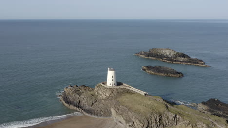 An-aerial-view-of-Twr-Mawr-Lighthouse-on-Ynys-Llanddwyn-island,-flying-left-to-right-around-the-lighthouse,-Anglesey,-North-Wales,-UK
