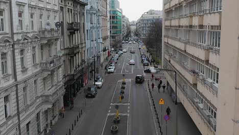 Aerial-view-of-people-and-traffic-in-middle-of-old-city-streets-in-Warsaw,-Poland---descending,-drone-shot