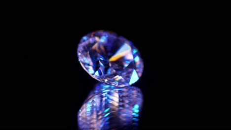 Macro-shot-of-high-quality-diamond-isolated-on-black-relfecting-surface,-illuminated-by-purple-and-blue-light
