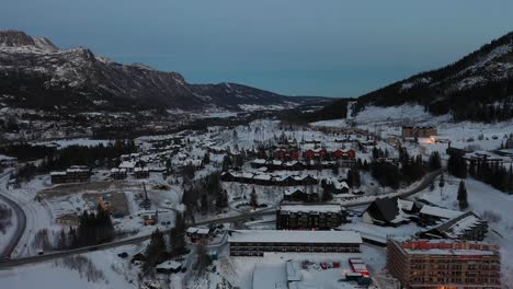 Late-evening-aerial-in-Hemsedal-Norway---Loads-of-leisure-homes-and-apartment-building-under-construction-in-foreground---Ascending-aerial-from-skiing-location-during-dusk-hours-revealing-full-valley