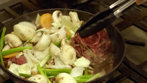 Cocinar-Un-Plato-Coreano-En-Una-Sartén-Con-Pinzas-De-Cocina
