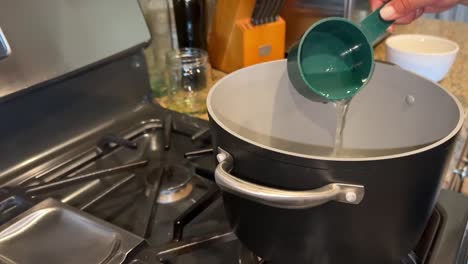 Measuring-water-into-a-hot-pot-of-boiling-water-to-cook-pasta