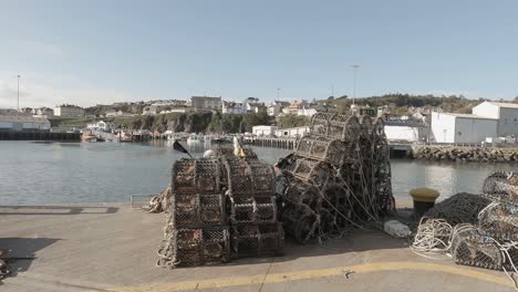 Lobster-pots-stacked-on-pier-await-fishermen-on-sunny-seaside-day
