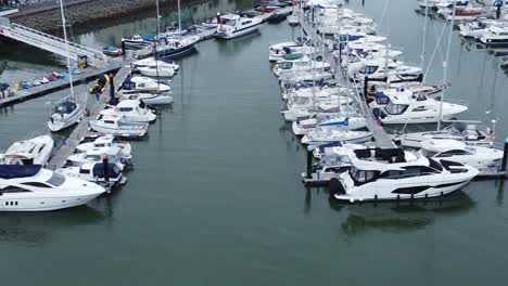 Aerial-Birdseye-view-across-wealthy-luxury-yachts-and-sailing-boats-moored-in-quaint-Conwy-town-harbour