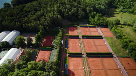 4K-Aerial-view-of-luxurious-red-clay-tennis-courts-in-a-rural-area