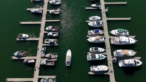 Top-down-aerial-shot-of-a-boat-slowing-traveling-to-their-assigned-dock-spot-in-a-marina