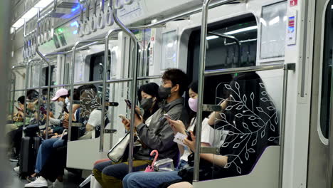 Close-up-shot-of-many-asian-Commuter-with-face-mask-travelling-in-metro-and-checking-smartphone---Seoul,South-Korea