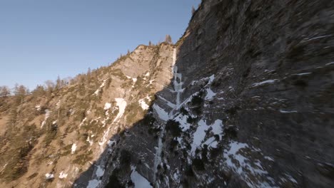 fpv-drone-flying-trough-a-frozen-waterfall-in-the-austrian-mountains-at-sunset