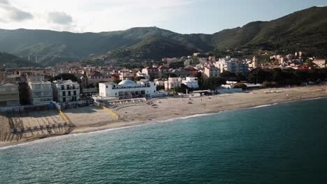 Drone-view-of-the-Mediterranean-with-a-sandy-beach,-town,-and-mountains