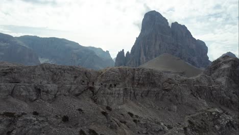 7-hikers-are-trekking-aside-a-mountain-trail-on-a-steep-cliff-with-outstanding-rock-formations-and-the-amazing-landscape-of-the-Dolomites-in-the-Background-in-North-Italy