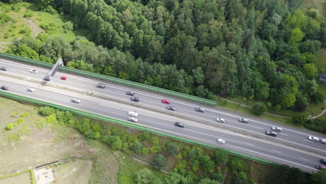 Aerial-top-down-shot-of-traffic-on-highway-surrounded-by-fields-and-forest-in-Gdynia,Poland