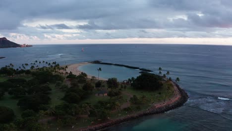 Tilt-down-aerial-panning-shot-of-Magic-Beach-in-Honolulu,-Hawaii-at-sunset