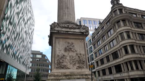 City-of-London-England-September-2022-Pan-up-establishing-shot-of-the-Fire-of-London-monument-with-tourists-below