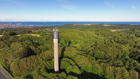 An-aerial-view-of-a-tower-built-in-a-wooded-area-on-a-sunny-summer-evening