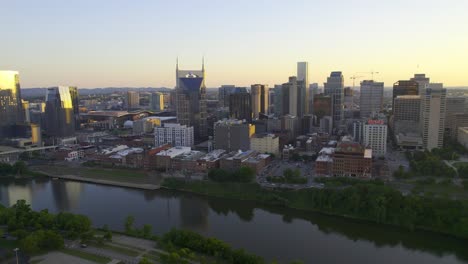 Aerial-view-of-the-Nashville-skyline-from-the-riverside,-sunny-summer-evening-in-Tennessee,-USA---tilt,-drone-shot