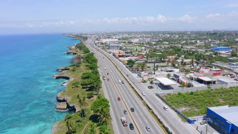 Drone-shot-of-driving-vehicles-on-Freeway-along-coastline-of-Santo-Domingo-city-during-summer