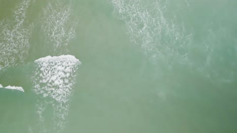 Overhead-aerial-view-of-waves-rolling-towards-beach