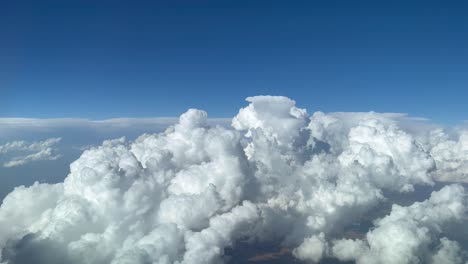 Impresionante-Vista-Piloto-Desde-La-Cabina-De-Un-Jet-Evitando-Nubes-De-Cúmulo-Tormentosas-En-Un-Cielo-Azul-Profundo-Y-Desordenado