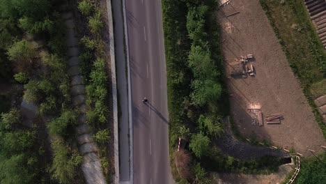 Boy-roller-skating-on-the-lonely-road-aerial-shot