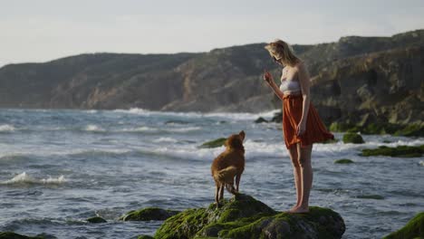 Glückliche-Junge-Frau-In-4K-Zeitlupe,-Die-Mit-Ihrem-Hund-Am-Guincho-Strand-In-Portugal-Spielt