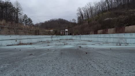 Slider-Footage-of-an-Empty-Overgrown-Wave-Pool-in-an-Abandoned-Rural-Waterpark-during-Winter