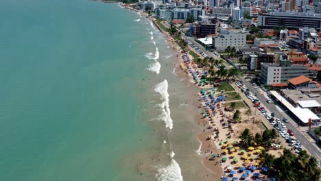 Tilt-up-wide-shot-of-intermares-beach-in-Cabedelo,-Brazil-with-Brazilians-and-tourists-enjoying-the-ocean-near-the-costal-capitol-of-Joao-Pessoa-in-the-state-of-Paraiba-on-a-warm-sunny-summer-day