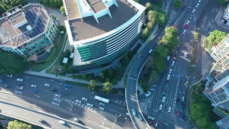 Top-down-drone-shot-of-an-office-building-at-the-intersection-of-Coronation-Drive-and-The-Go-Between-Bridge,-showcasing-traffic-below-on-a-sunny-afternoon