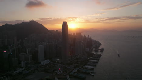 Puesta-De-Sol-Detrás-Del-Edificio-Del-Centro-Financiero-Internacional-De-Hong-Kong,-Gran-Angular-Cinematográfico-Que-Establece-Un-Disparo-De-Drones