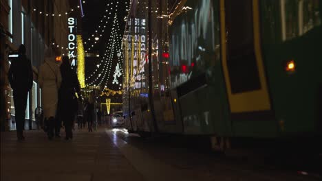 Low-angle-transit-tram-passes-on-city-street-decorated-for-Christmas