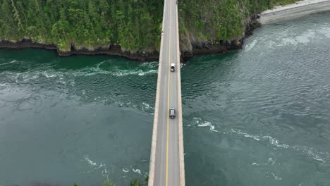 Overhead-aerial-view-of-cars-driving-along-the-Deception-Pass-bridge-over-the-Pacific-Ocean